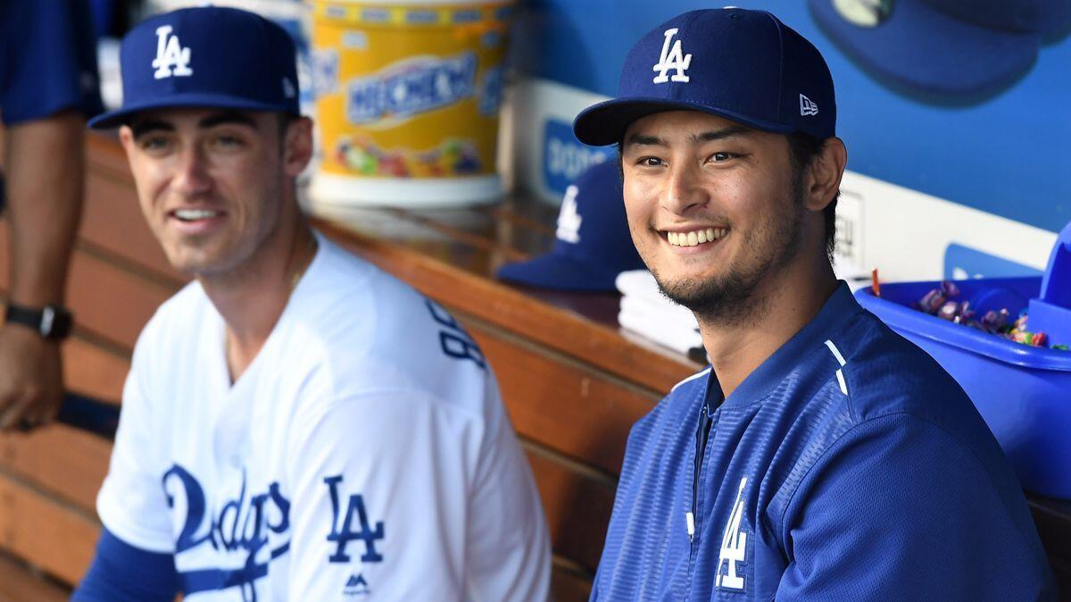 Dodgers' Cody Bellinger, left, and pitcher Yu Darvish smile in the dugout at Dodger Stadium Tuesday.