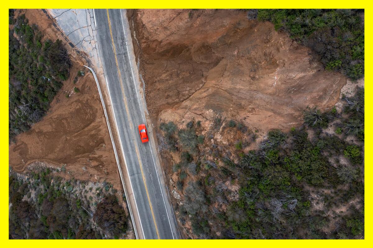 An aerial view of a red car driving through a landslide area