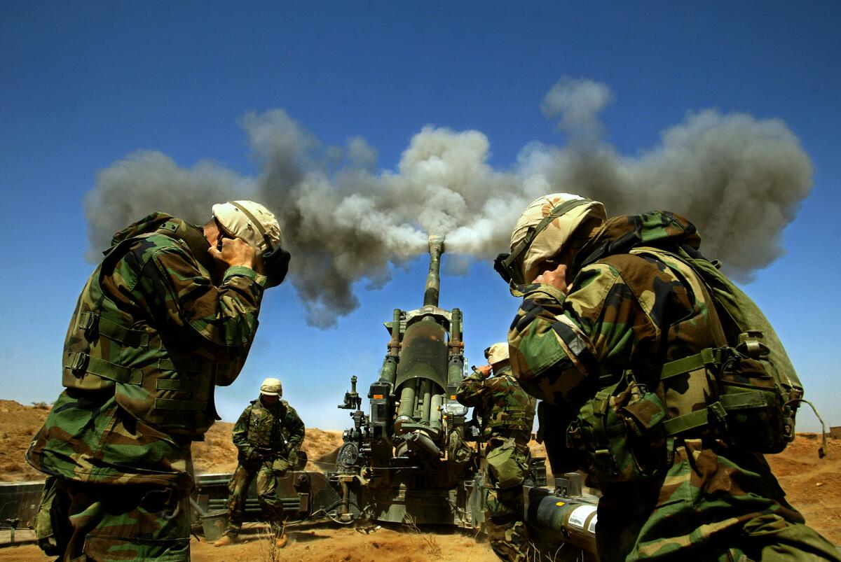 Marines hold their ears upon the release of an artillery round 