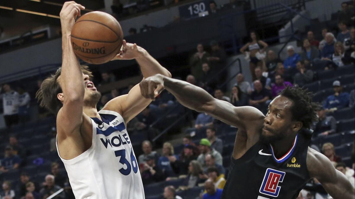 Clippers' Patrick Beverley, right, knocks the ball away from Minnesota Timberwolves' Dario Saric in the first half on Tuesday in Minneapolis.