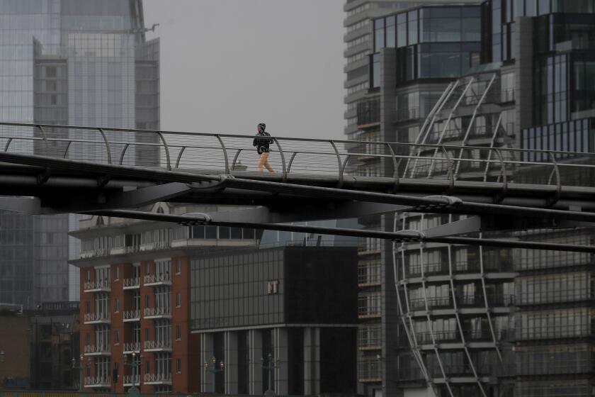 A runner crosses the Millennium Bridge as the coronavirus lockdown continues in London, Thursday, March 25, 2021. All gyms remain closed until at least April. (AP Photo/Kirsty Wigglesworth)