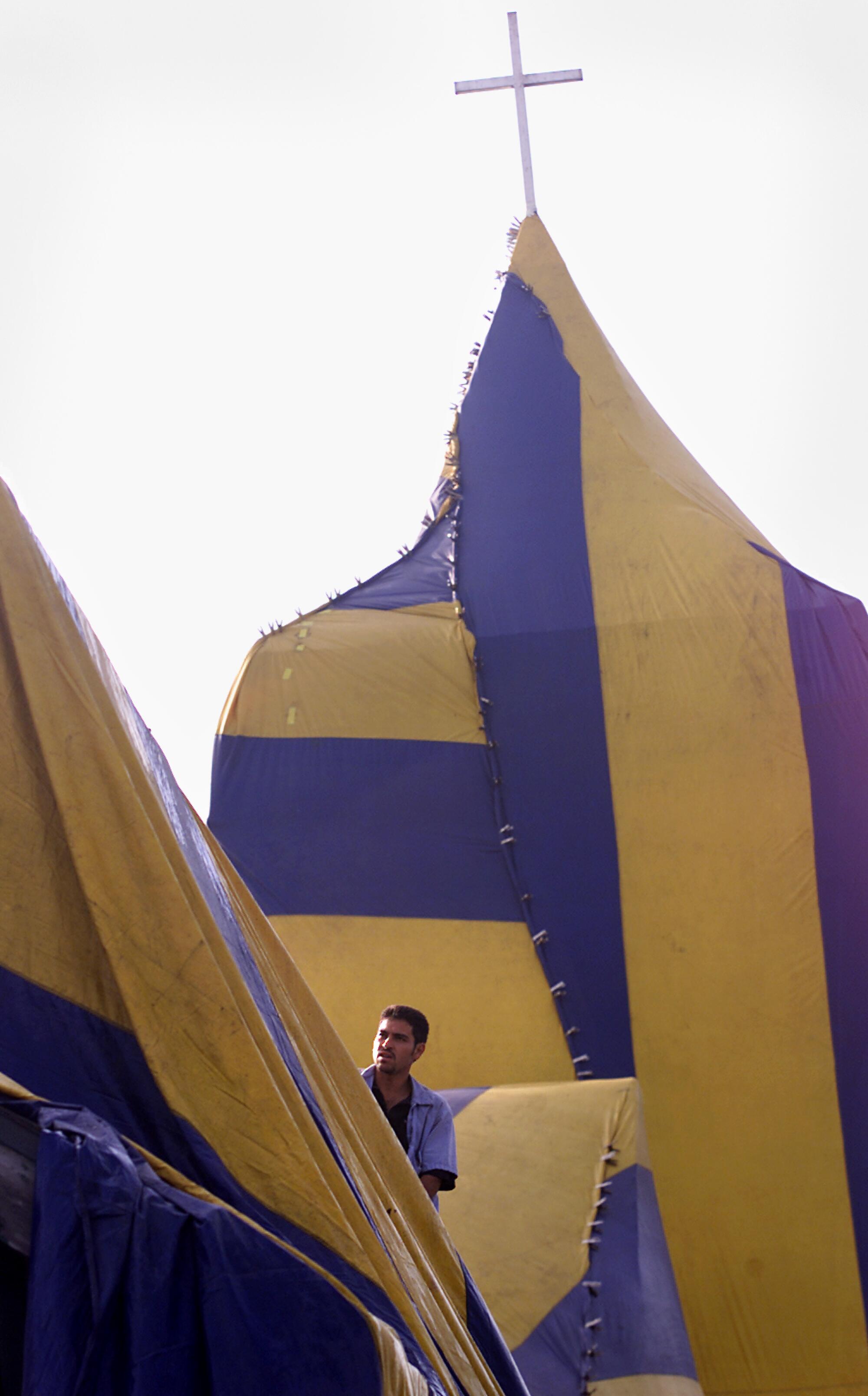A man stands on the roof of a building that has been covered with a fumigation tent.