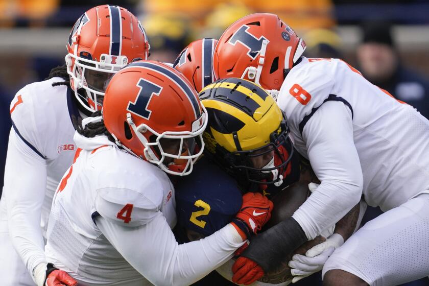 Michigan running back Blake Corum (2) is stopped by Illinois defensive lineman Jer'Zhan Newton (4) and linebacker Tarique Barnes (8) in the first half of an NCAA college football game in Ann Arbor, Mich., Saturday, Nov. 19, 2022. (AP Photo/Paul Sancya)