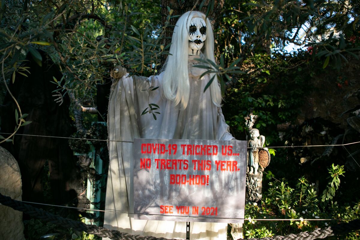 A sign under a ghost decoration says "COVID-19 tricked us. No treats this year. Boo-hoo! See you in 2021"