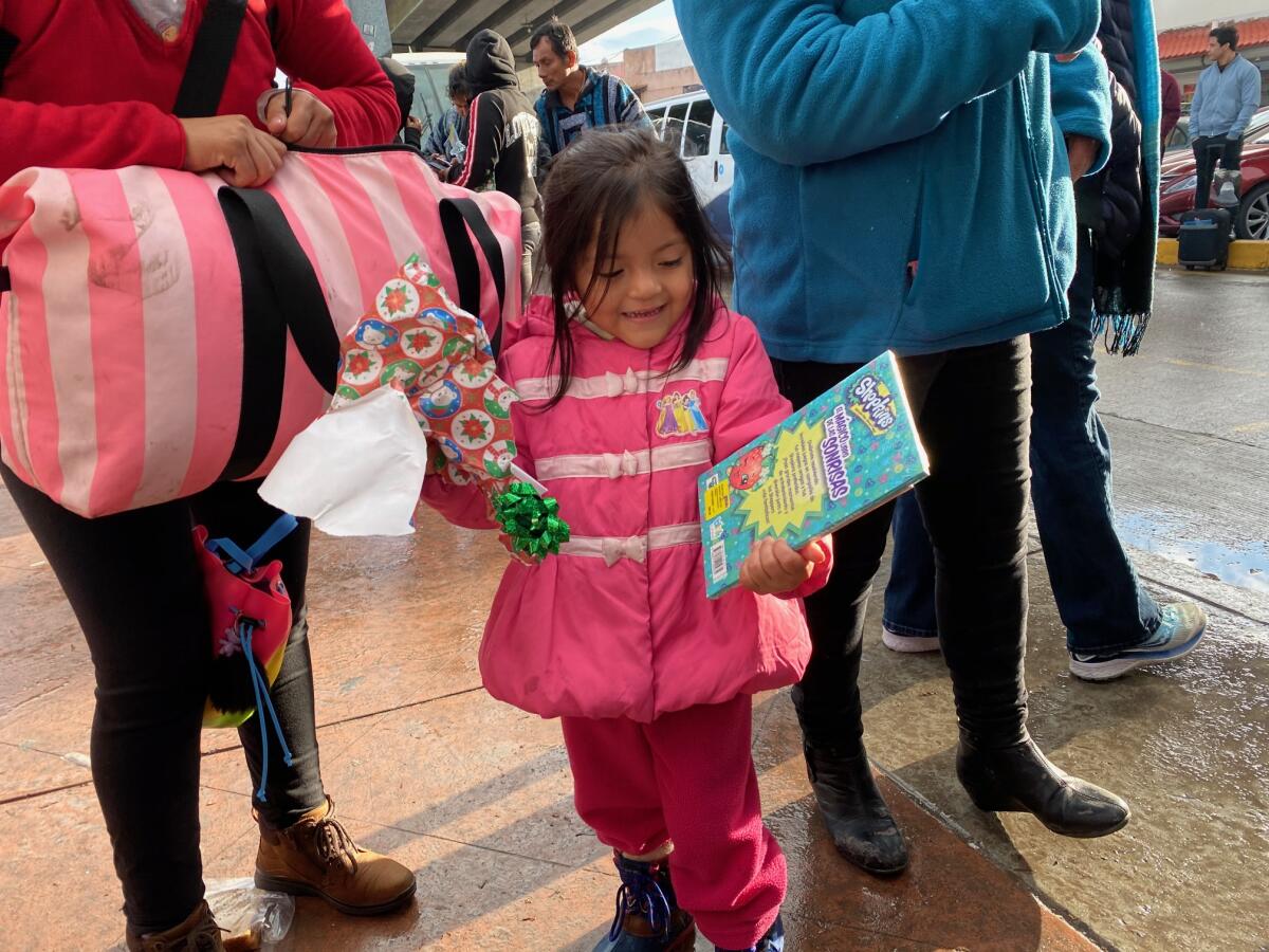 Sofia Nhanelii, 4, from Oaxaca, Mexico, opens a coloring book on Christmas Eve while her family waits for their turn to make an asylum claim. A group of volunteers known as PBJTJ handed out presents to children stuck at the border on Tuesday.