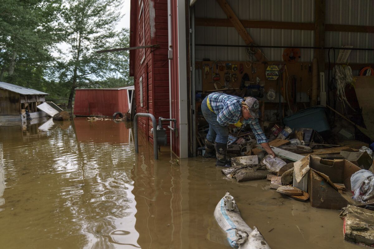 A woman sorts through personal mementos in the barn of her parents' home badly damaged by flooding.
