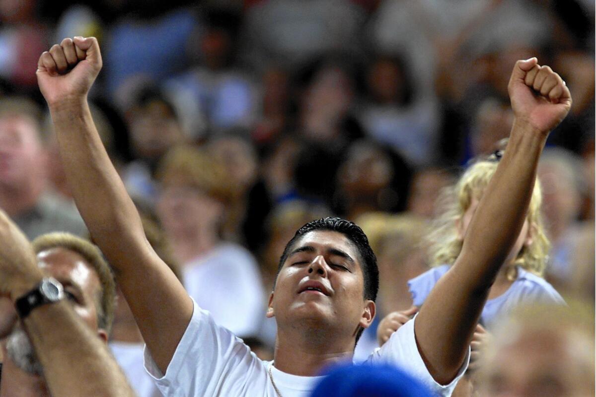 Job Jimenez of Orange lifts his arms as the Harvest Crusade begins at Edison Field of Anaheim in 2000.