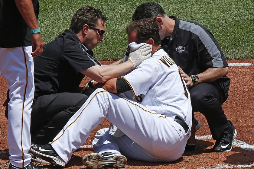 Pittsburgh Pirates pitcher Ryan Vogelsong, center, is helped by team trainers after being hit in the head by a pitch from Colorado Rockies pitcher Jordan Lyles in the second inning on Monday.