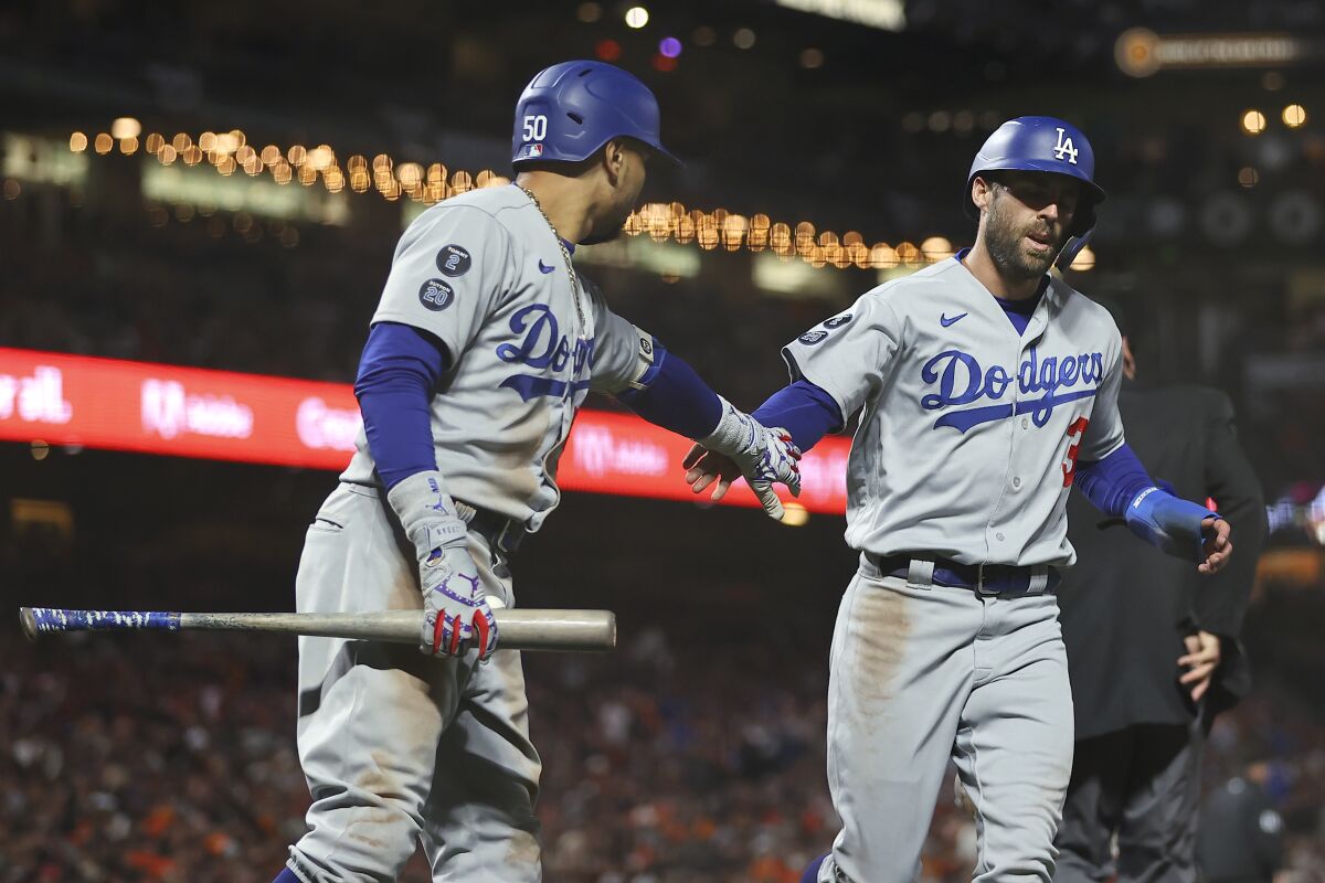 Los Angeles Dodgers' Chris Taylor, right, is congratulated by Mookie Betts after scoring against the San Francisco Giants during the eighth inning of Game 2 of a baseball National League Division Series Saturday, Oct. 9, 2021, in San Francisco. (AP Photo/John Hefti)