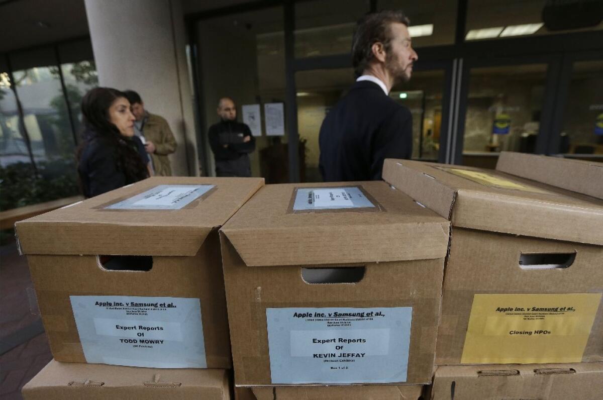 Clerks stand behind boxes containing documents related to the Apple versus Samsung case outside a federal courthouse in San Jose.
