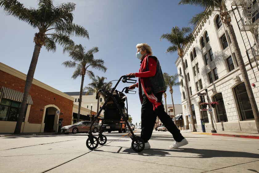 VENTURA, CA - APRIL 22: Local historian Cynthia Thompson crosses South California Street on East Main in downtown Ventura Wednesday morning as Ventura County on Saturday modified its stay-at-home order to permit some businesses to reopen and some gatherings to take place for the first time since the restrictions were issued to fight the spread of the coronavirus COVID-19. Cynthia said "I think this is absolutely necessary. It's exactly like the plague of 1918. Mandatory masks, closing everything down, and they used churches as hospitals." "You have to give people hope, but you have to be very cautious. It's an invisible enemy." She added. Ventura on Wednesday, April 22, 2020 in Ventura, CA. (Al Seib / Los Angeles Times)