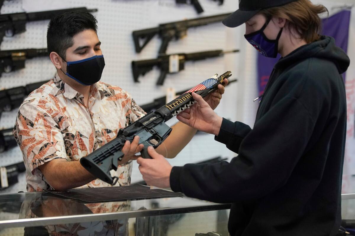 A salesman shows a gun buyer a custom-made AR-15-style rifle