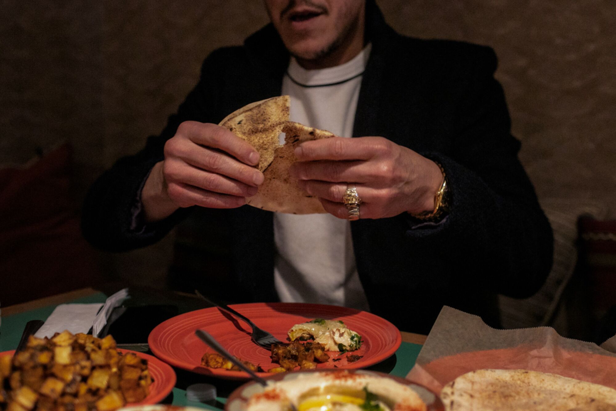 A man tears some pita bread at a Middle Eastern restaurant.