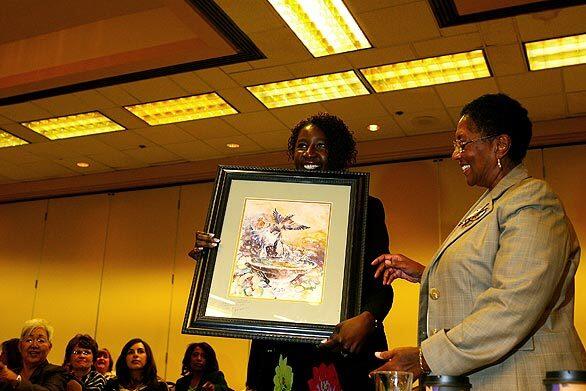 Carol Stanford, left, who directs the nursing diversion program, presents a painting given to the Board of Registered Nursing by a graduate of the program to Ruth Ann Terry, board executive officer who has since resigned.