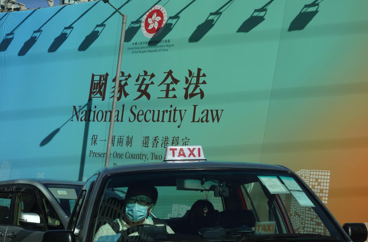 A taxi drives past a banner touting the Hong Kong National Security Law.