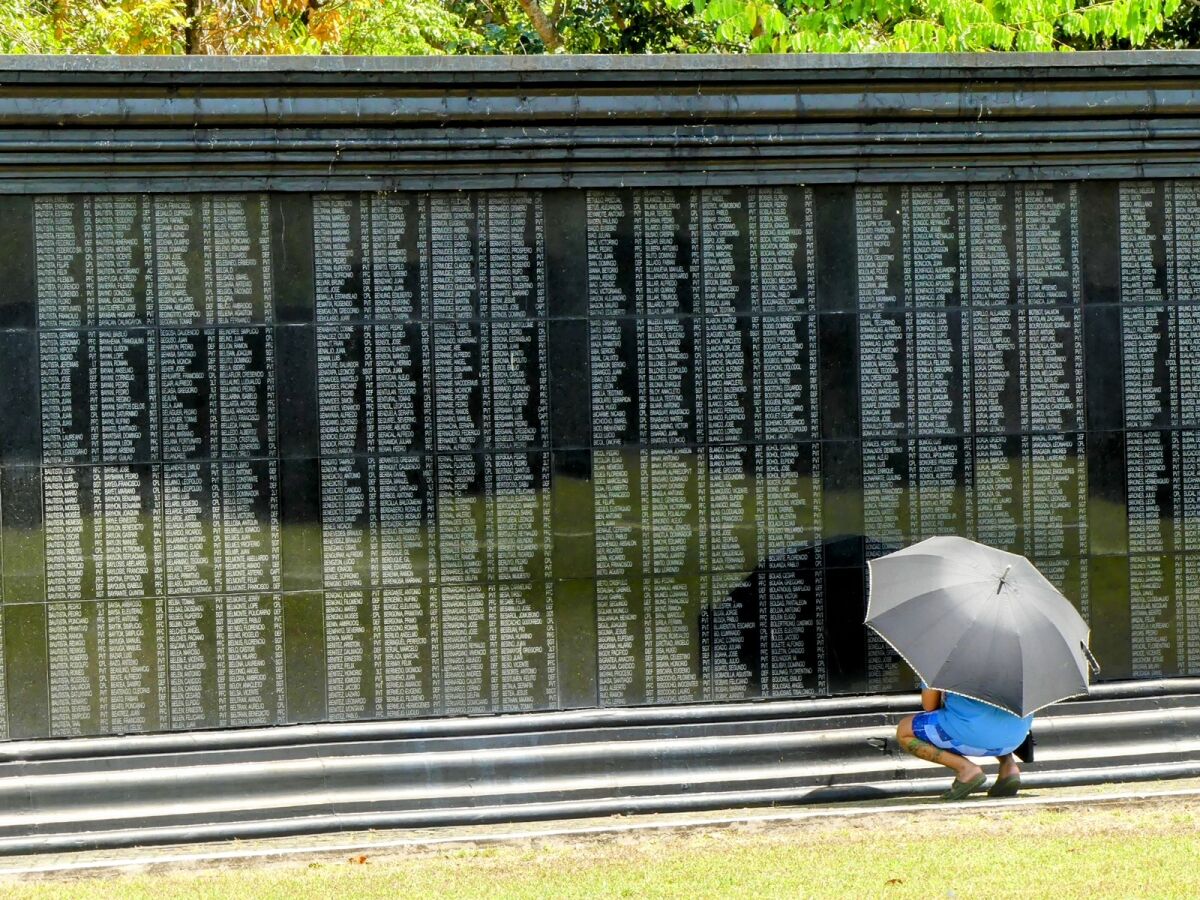 A visitor studies the names on a memorial to 26,000 U.S. and Philippine soldiers.