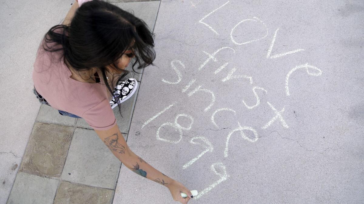 Misa Rashid, a sophomore at Azusa Pacific University, writes her sentiment in chalk following a rally by the LGBTQ Christian community at Azusa Pacific University to show support after the school reinstated a ban on same-sex relationships on campus.