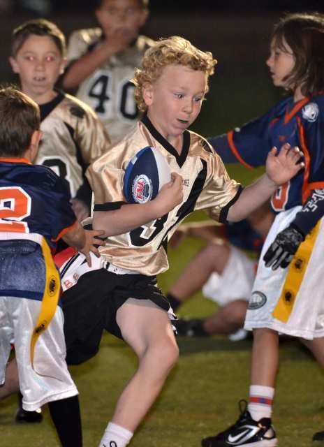 Seven-year-old Brett Bruder (32) of the Commodores runs with the ball during the Newport Mesa Friday Night Lights flag football program's Opening Day.