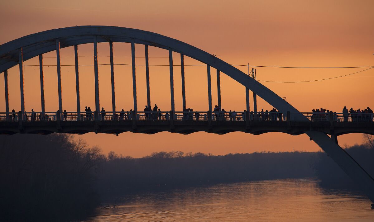 People walk and stop along the Edmund Pettus Bridge at dusk March 2015 in Selma.