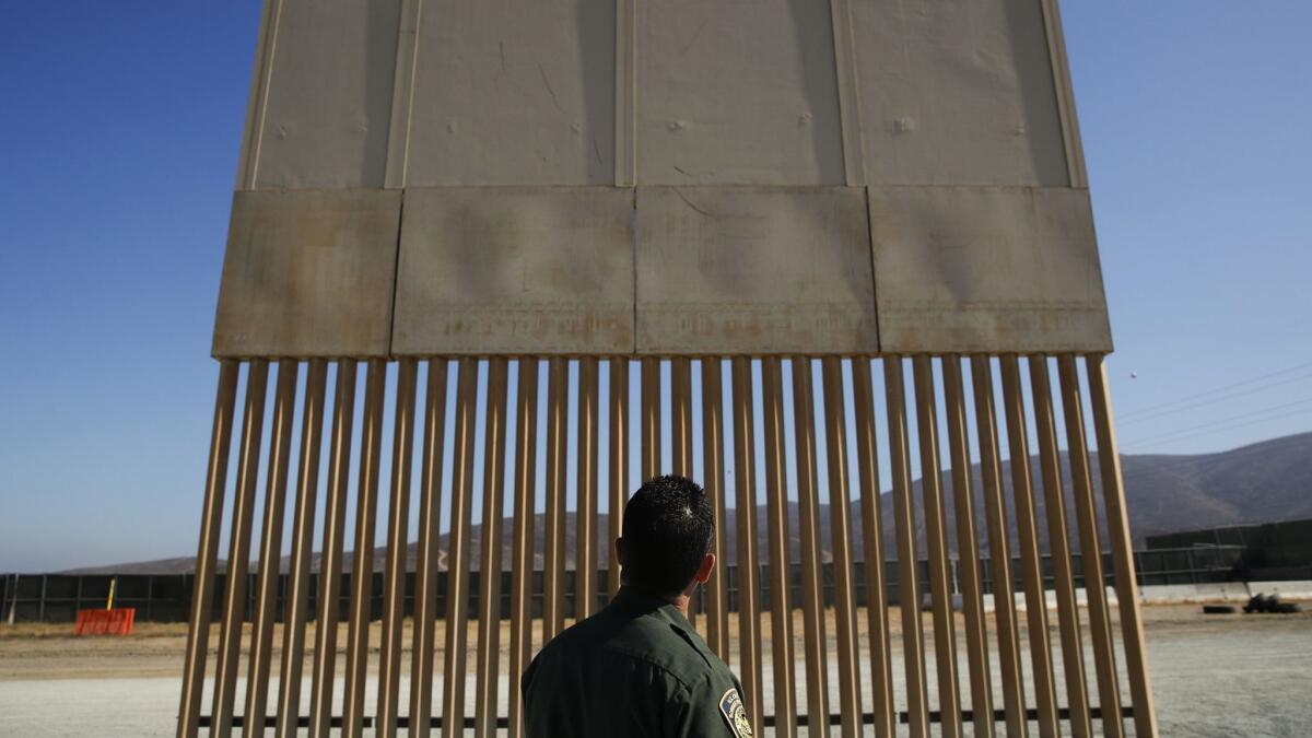 A U.S. Border Patrol agent looks at one of the border wall prototypes June 28 in San Diego.