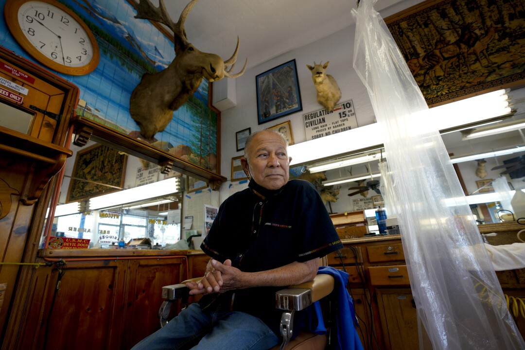 Johnny Gomez sits in one of the barber chairs.