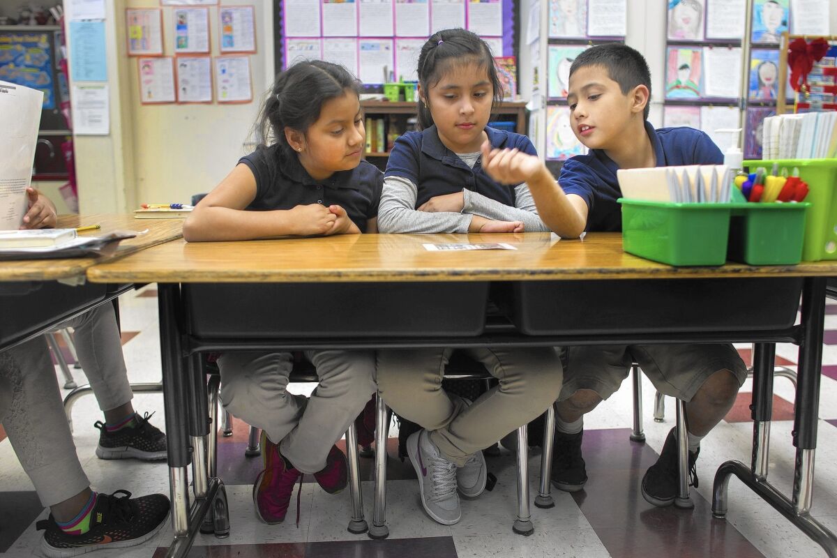 Omar Rodriguez, right, works with Daphne Osori, left, and Sherlyn Rodriguez to build their English conversation skills at Gratts Elementary School in Los Angeles. Two congressional bills aim to fill the holes of No Child Left Behind.