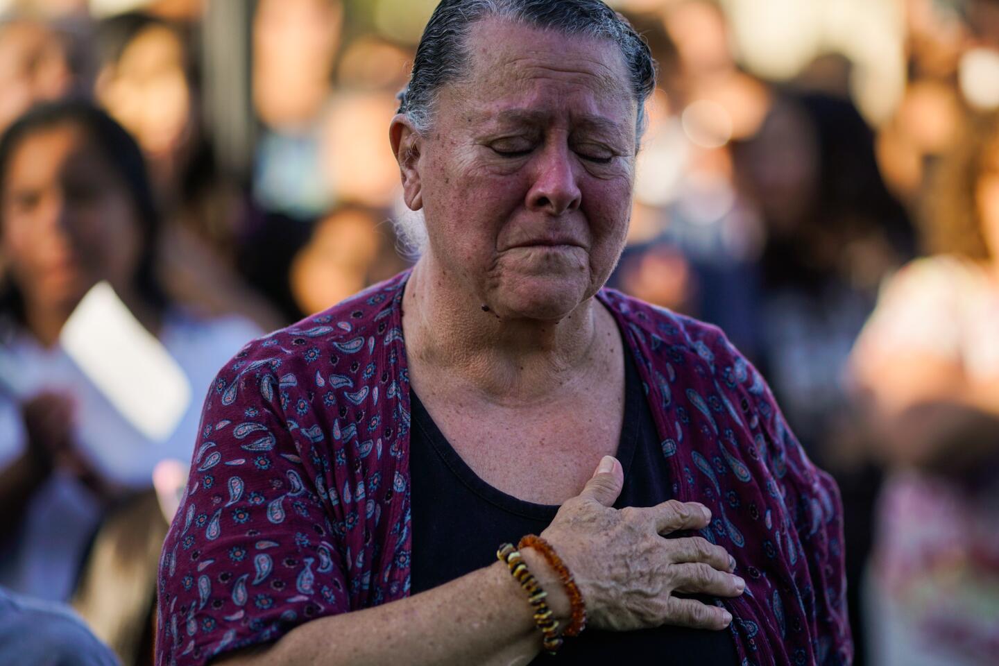 A woman is overcome with grief during the singing of the National Anthem during a candlelight vigil at Gilroy City Hall on Monday.