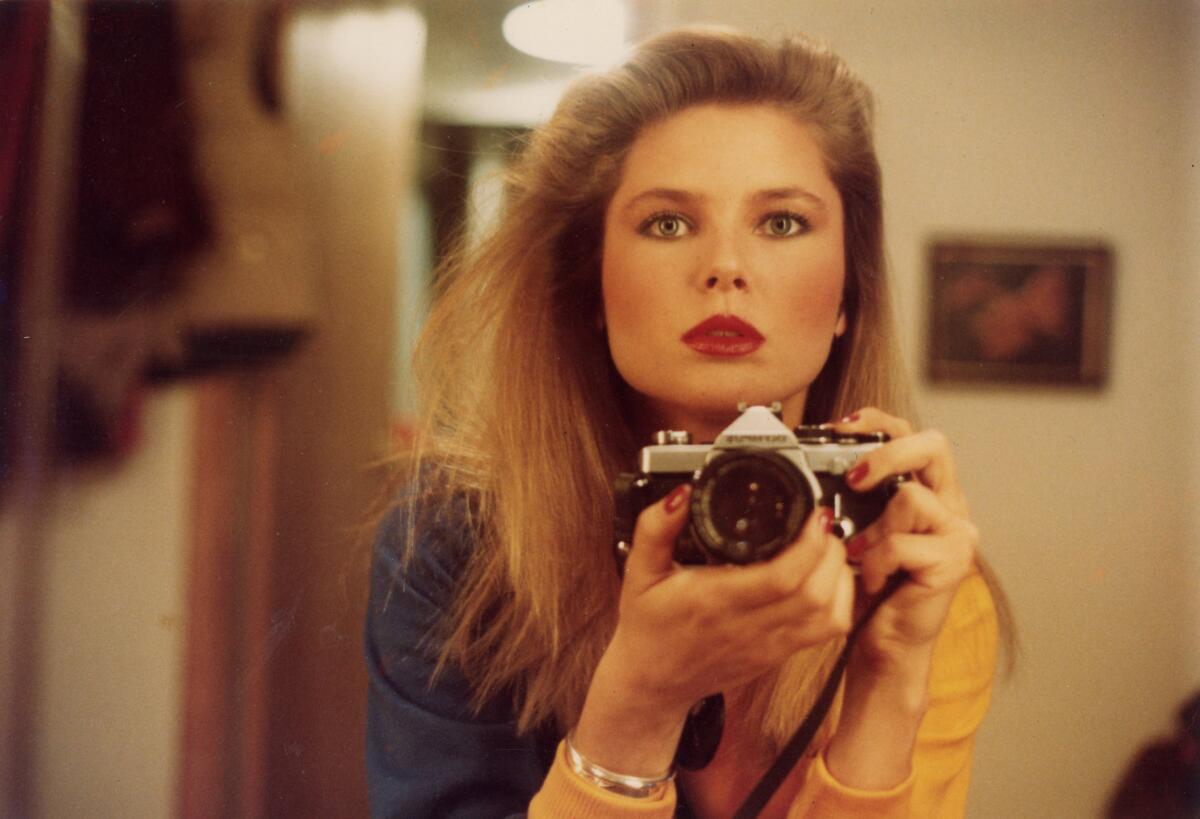 A reflection of Christie Brinkley taking a photograph of herself.