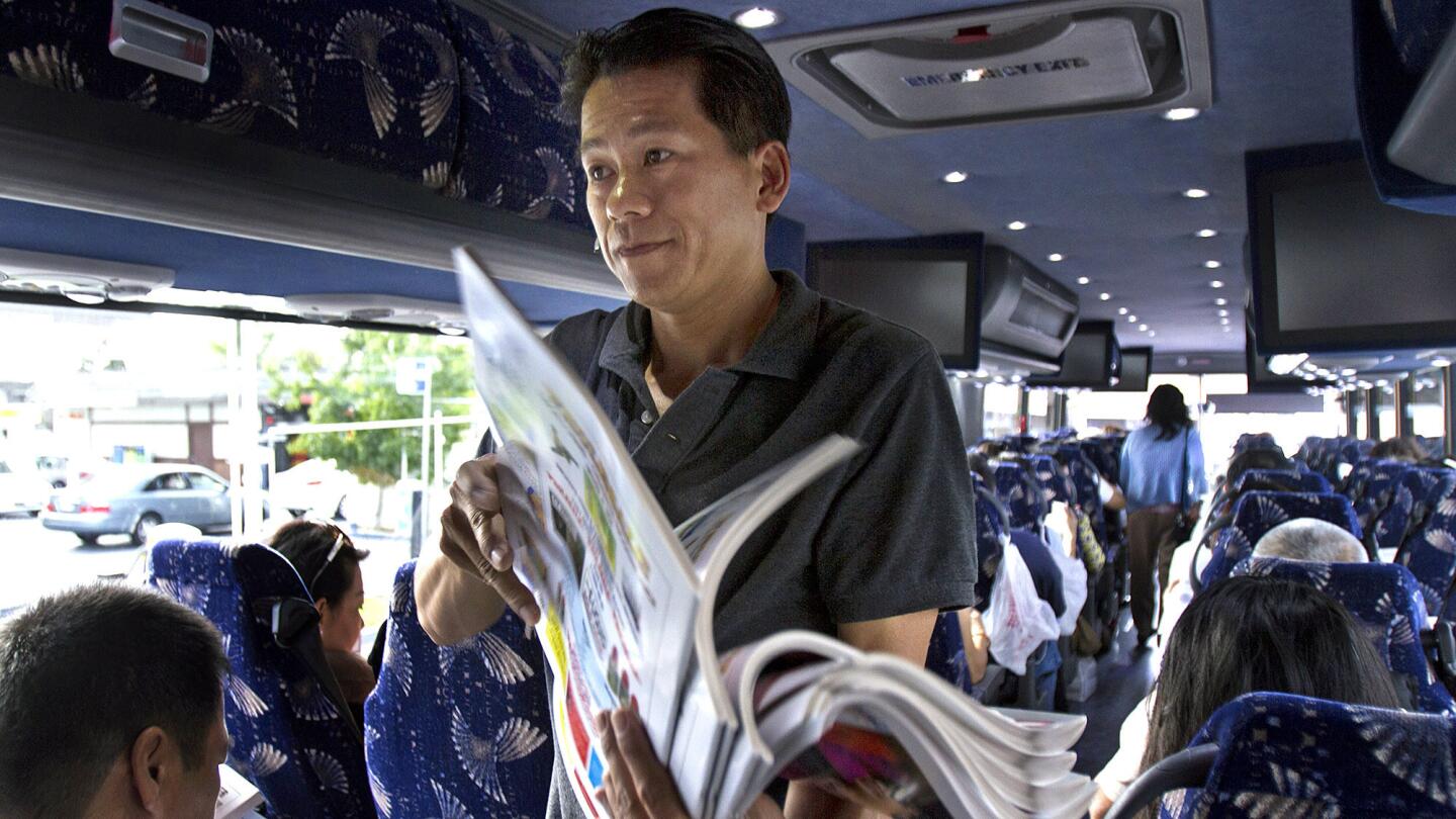 Bus driver Tam Le passes out Vietnamese newspapers to passengers before heading to San Jose. The Xe Do Hoang bus line connects Little Saigon with San Jose, the two largest Vietnamese American communities in the country.