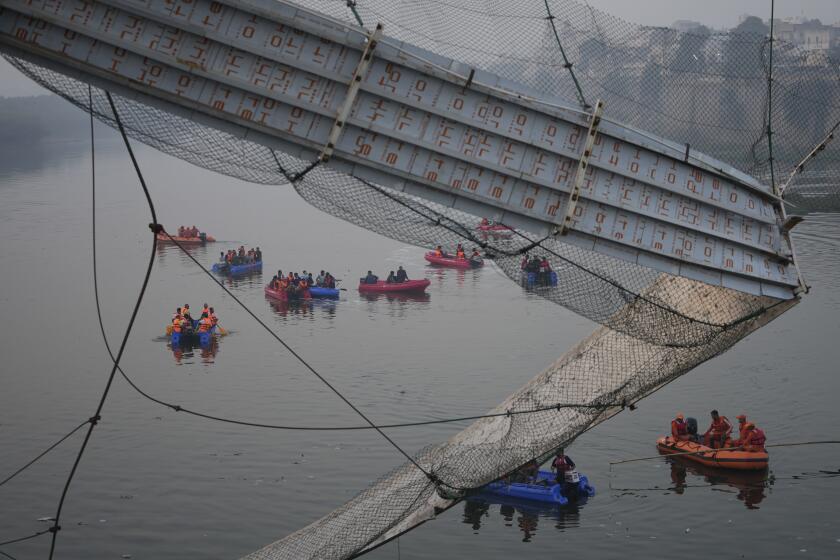 Rescuers on boats search in the Machchu river next to a cable suspension bridge that collapsed in Morbi town of western state Gujarat, India, Monday, Oct. 31, 2022. The century-old cable suspension bridge collapsed into the river Sunday evening, sending hundreds plunging in the water, officials said. (AP Photo/Ajit Solanki)