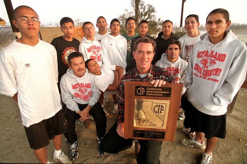 McFarland High's cross-country runners, who won a seventh state championship for their school in 1999, pose with coach Jim White, who holds the team's trophy.
