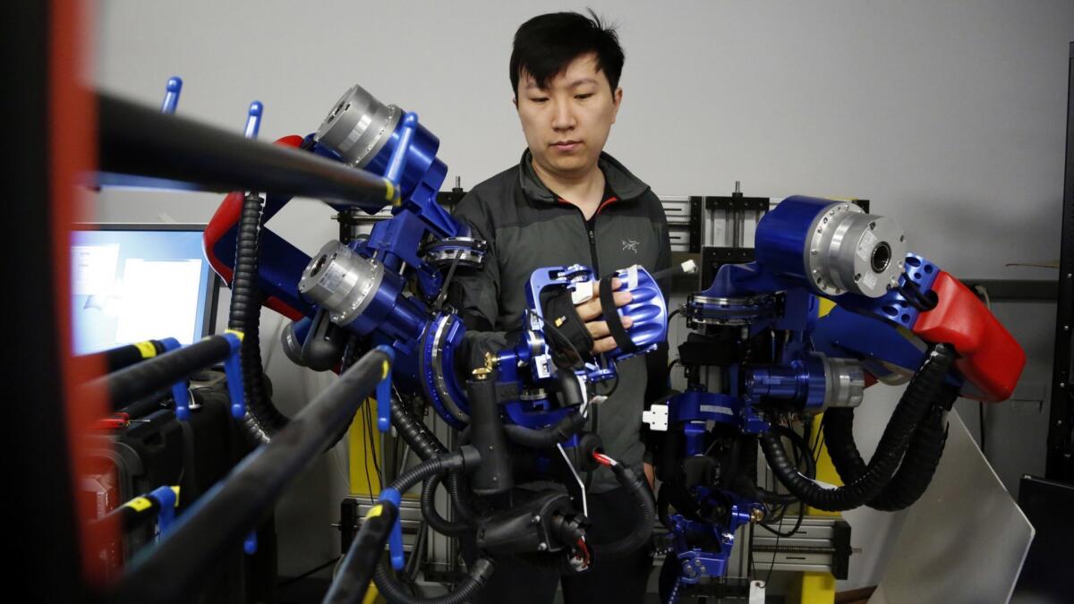 Yang Shen, a doctoral candidate in robotics at UCLA, demonstrates how an exoskeleton robot could help stroke patients recover the ability to move.