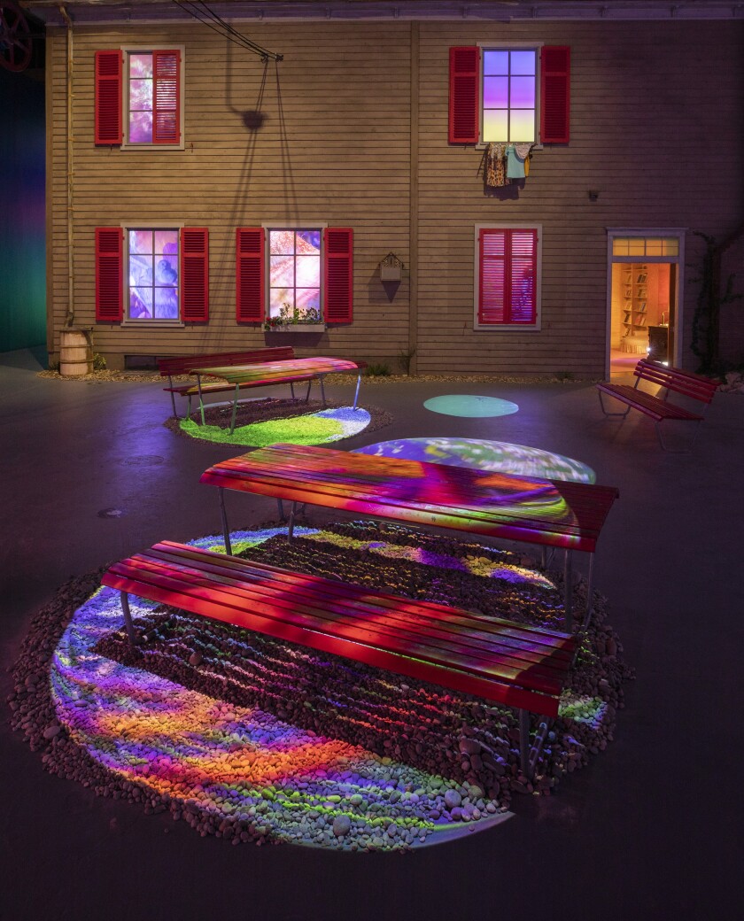 Colorful video projections sweep across the facade of a house and its courtyard.