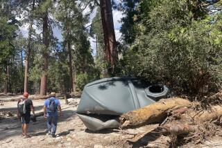 Jason Liou, left, and Rey Cano survey the damage to a water tank at Camp River Glen in the San Bernardino National Forest following Tropical Storm Hilary last August.