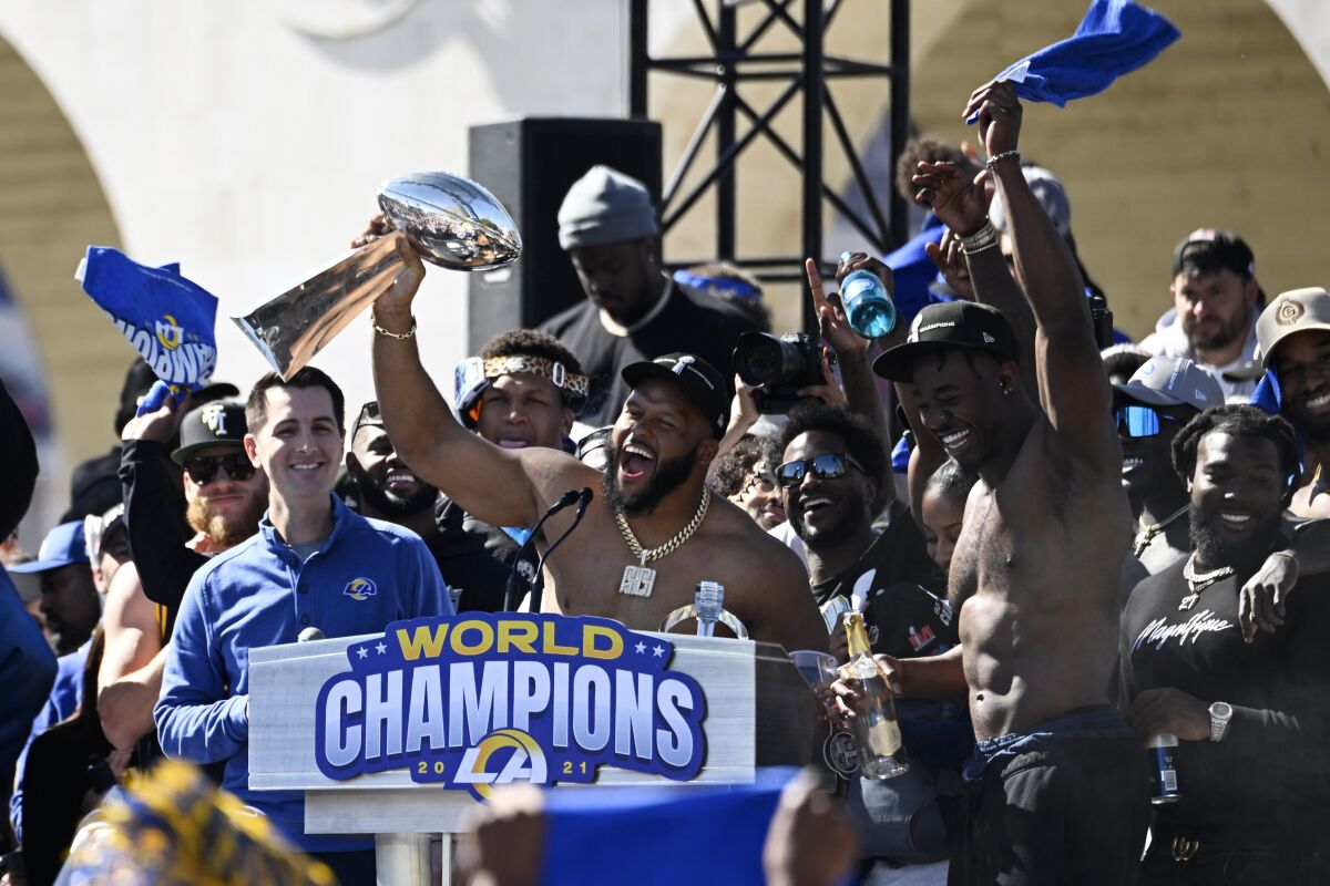Los Angeles Rams defensive lineman Aaron Donald, center, holds up the Vince Lombardi Super Bowl trophy as he celebrates with teammates during the team's victory celebration and parade in Los Angeles, Wednesday, Feb. 16, 2022. The Rams beat the Cincinnati Bengals Sunday in the NFL Super Bowl 56 football game. (AP Photo/Kyusung Gong)