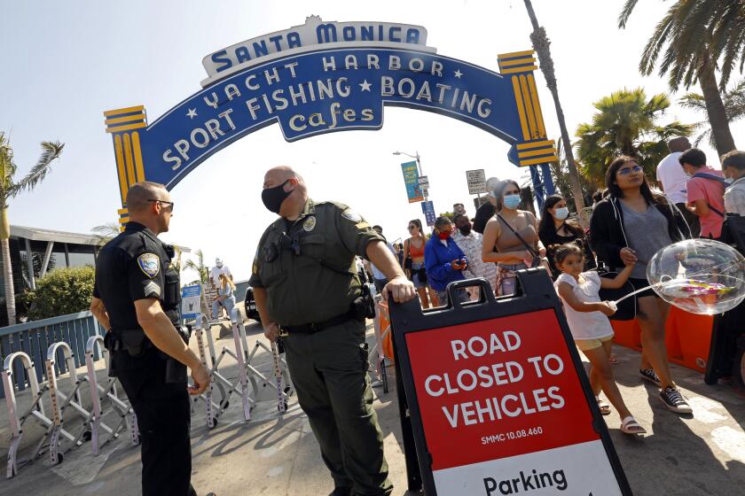 Santa Monica, CALIFORNIA—May 30, 2021—Police monitor the people entering Santa Monica Beach, which is at reduced capacity this Memorial Day. People flock to Santa Monica Pier and Santa Monica beach on Memorial Day, May 30, 2021. (Carolyn Cole / Los Angeles Times)