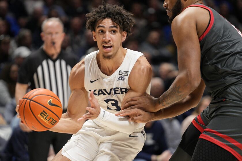 Xavier guard Colby Jones (3) controls the ball against St. John's Joel Soriano, right, during the first half of an NCAA college basketball game, Saturday, Feb. 4, 2023, in Cincinnati. (AP Photo/Jeff Dean)