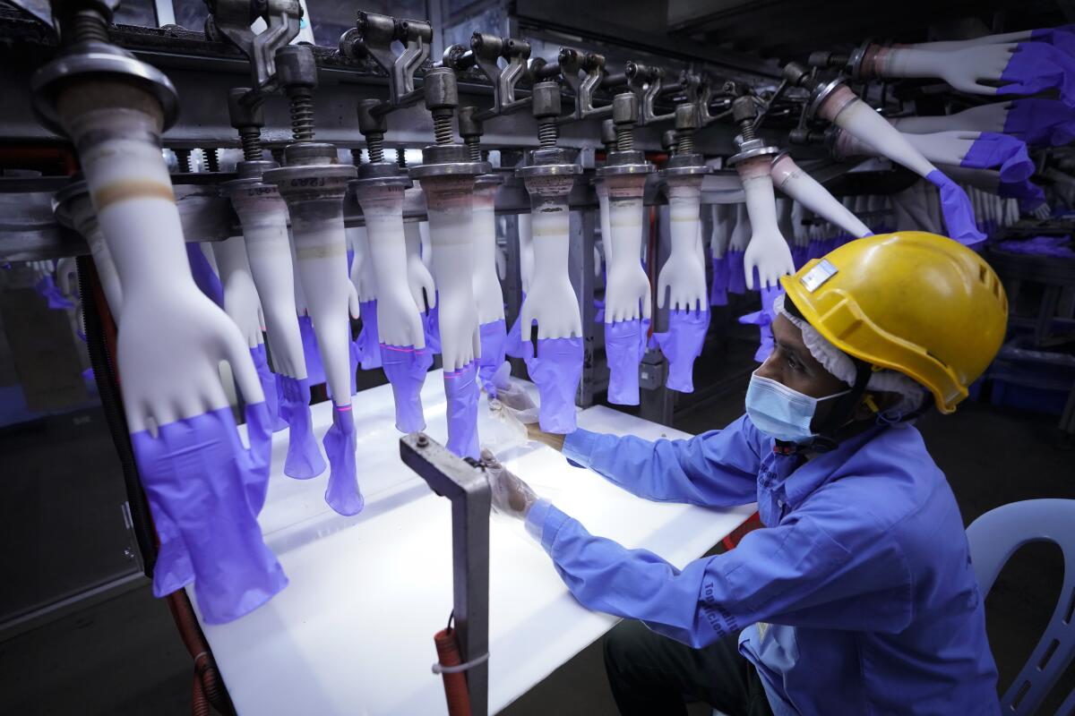 A worker inspects disposable gloves at a glove factory