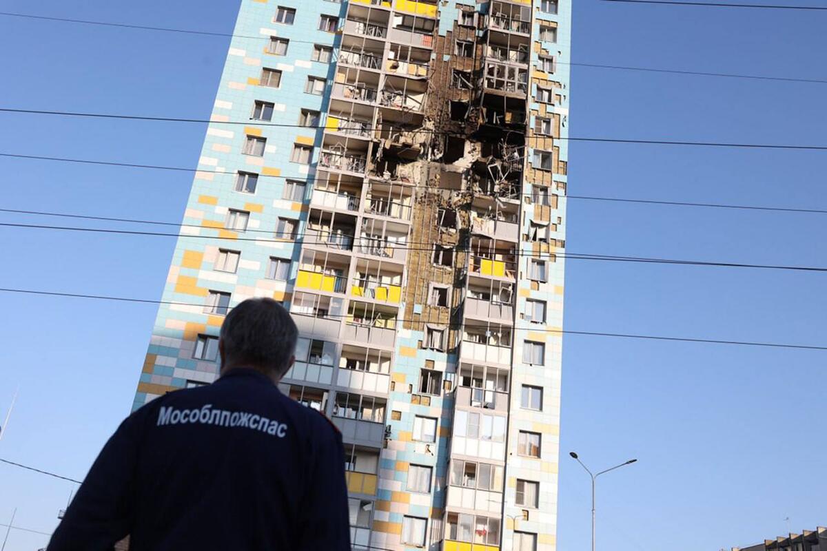 A damaged multi-story residential building viewed from the ground