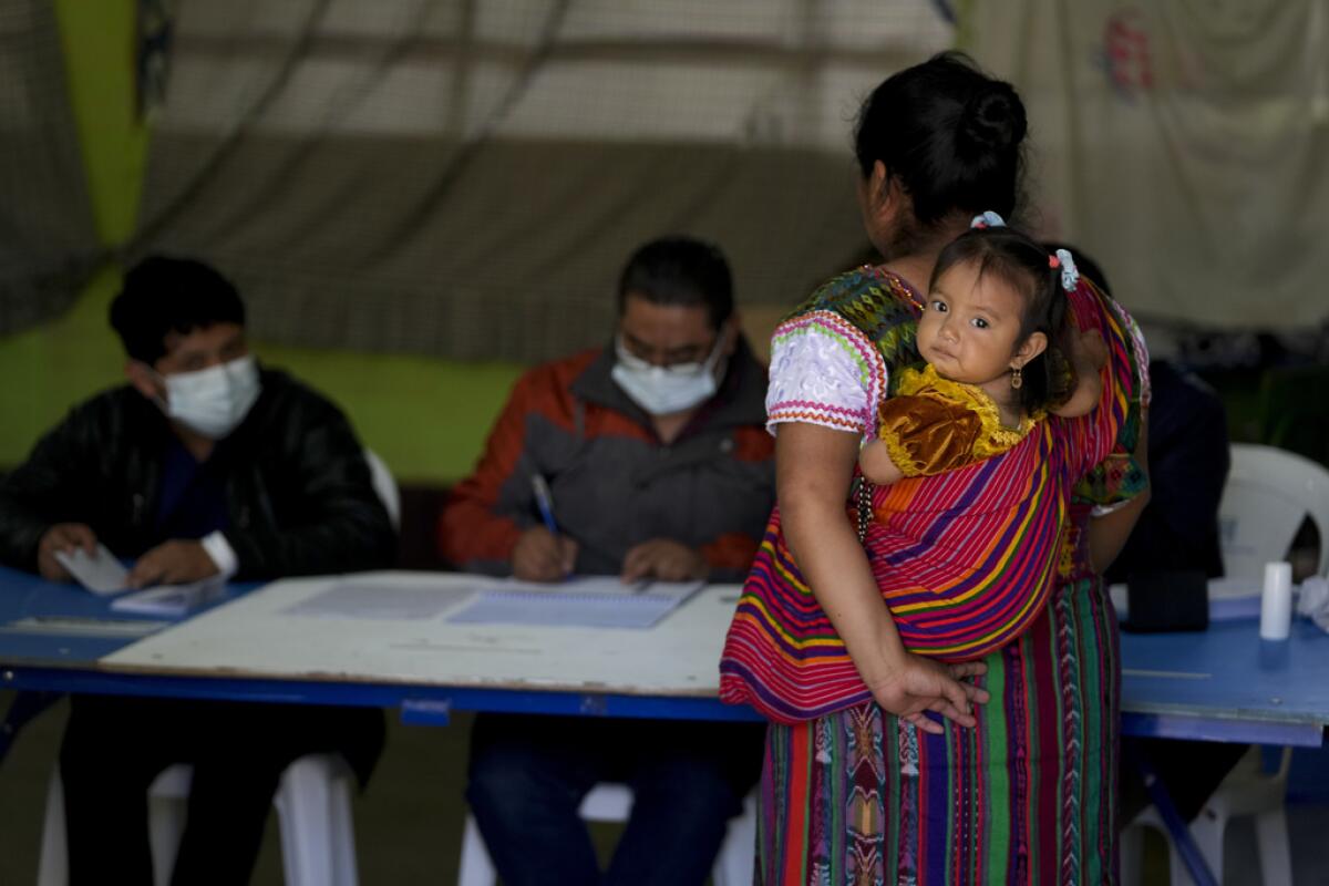 Una mujer llega a un centro de votación para votar con una niña en brazos 