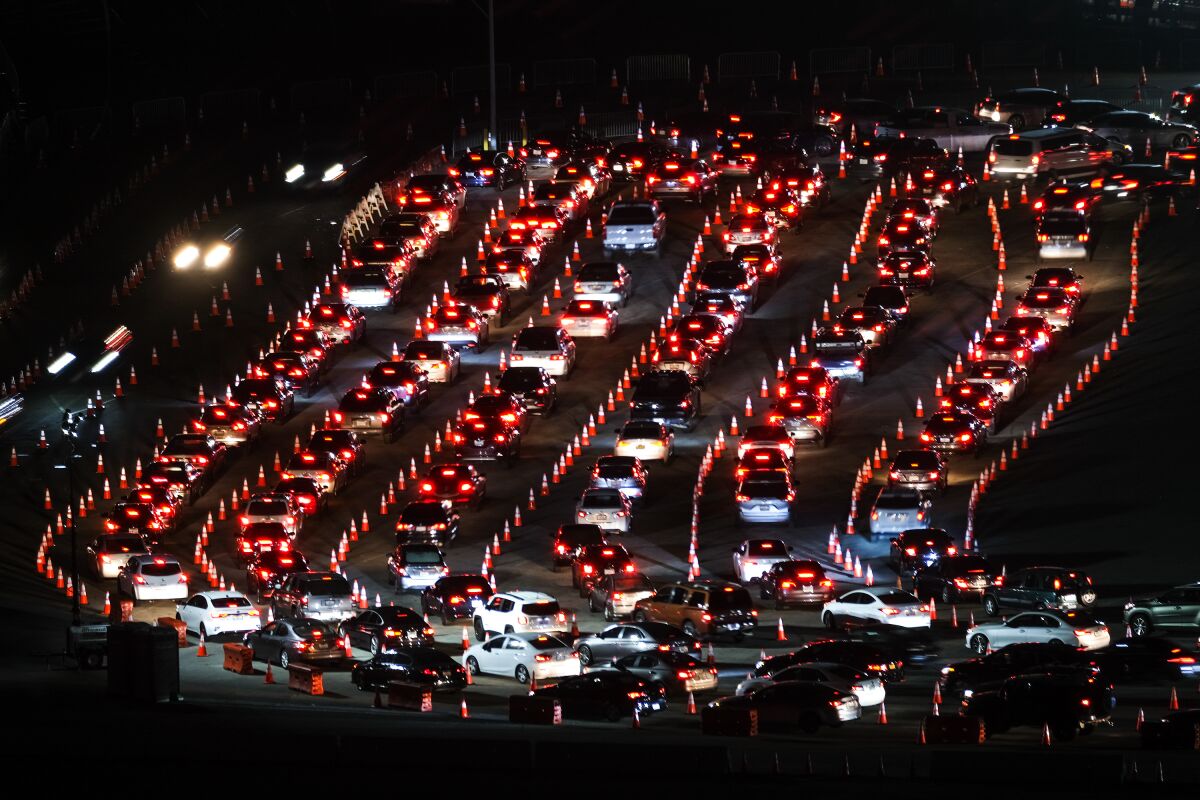 Snaking rows of taillights are seen after dark in a parking lot.