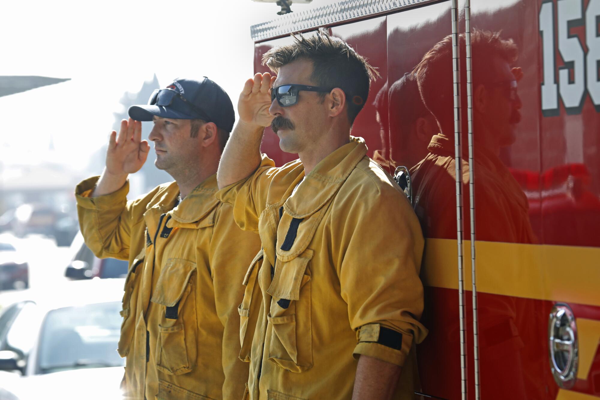 Two firefighters salute
