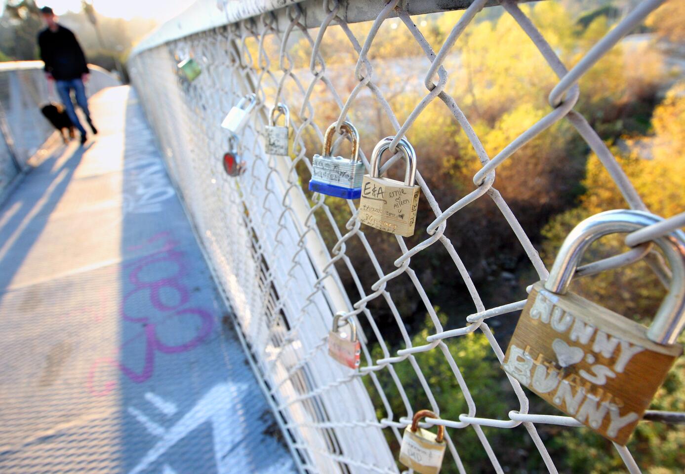A pedestrian and his dog walk by love locks attached to the Sunnynook Pedestrian bridge in Atwater that follow a world wide romantic tradition.