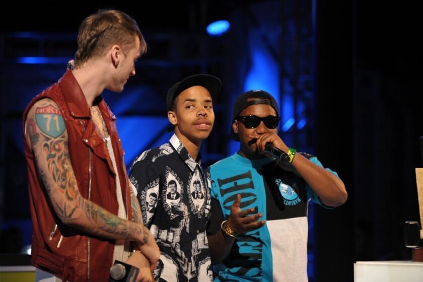 Host Machine Gun Kelly, left, presents the Breaking Woodie to Earl Sweatshirt, center, on stage at the mtvU Woodie Awards on Thursday, March 14, 2013, in Austin, Texas. Speaking at right is Domo Genesis.