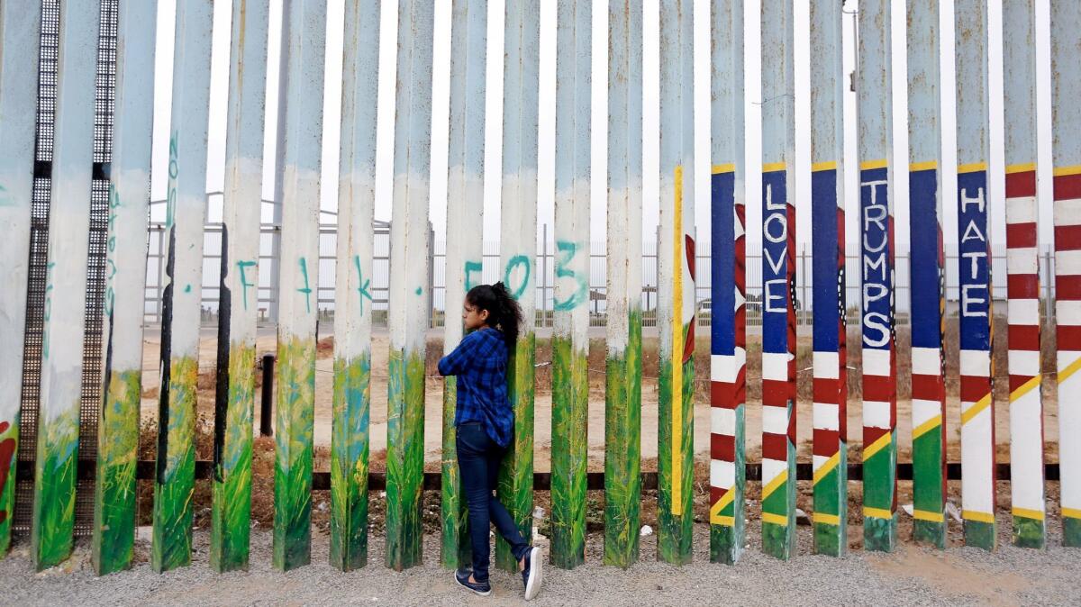 Jade Vega, 14, of Peru peers through the fence at Friendship Park at the beach along the U.S.-Mexico border in Tijuana. Vega, who says she is a U.S. citizen, was visiting her mother in Tijuana for the summer.