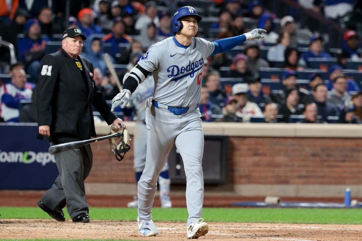 Dodgers star Shohei Ohtani tosses his bat after hitting a three-run home run.