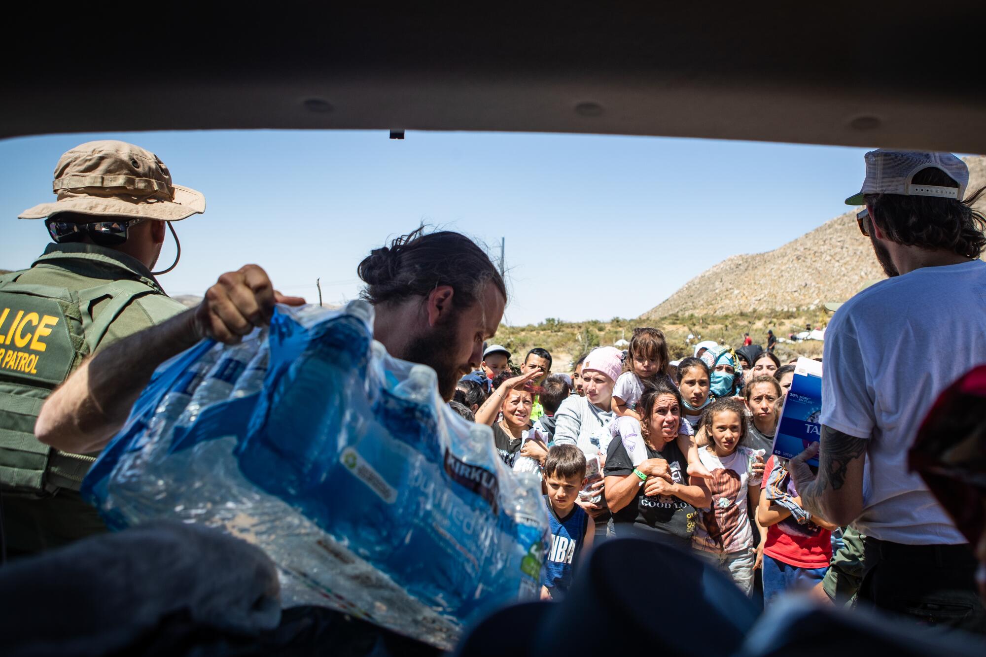 Jeff Osborne and David Lampley hand out water and other supplies to migrants in on Friday in Jacumba Hot Springs.