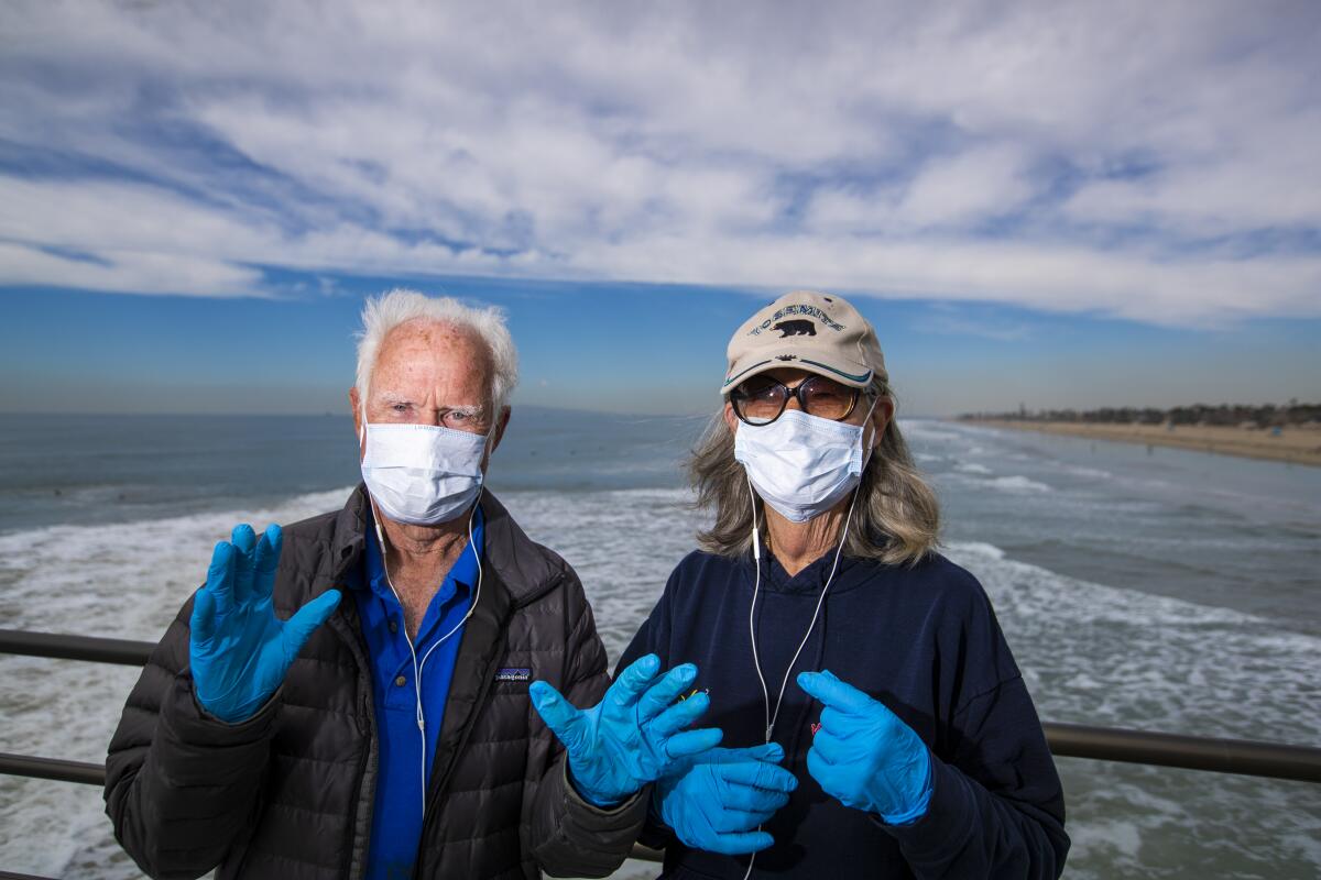 Dr. Dallas Weaver, 79, and his wife, Janet Weaver, 75, in masks and gloves, on Huntington Beach Pier.