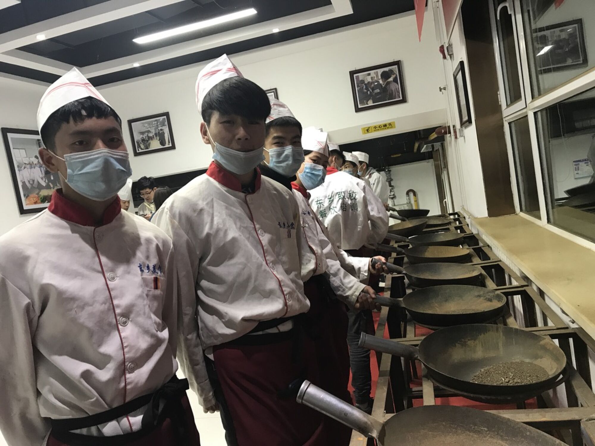 Dongxiang teenagers practice flipping woks at a vocational school near Linxia.