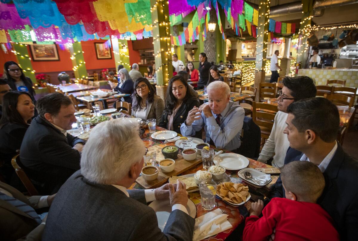 People talk and sit around a big table in a colorful restaurant.